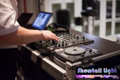 Un DJ ajuste les réglages sur une table de mixage lors d'un événement en intérieur.