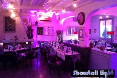 Salle de réception décorée avec des lumières violettes, tables dressées et ambiance chaleureuse.