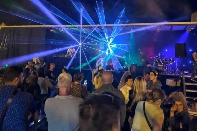 Foule rassemblée devant une scène en plein air avec jeux de lumières et musique en direct.