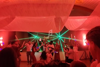 Des personnes dansent sous des jeux de lumière colorés dans une salle décorée de voilages suspendus.