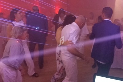 Des personnes dansent dans une salle éclairée par des lumières colorées et des effets de laser.