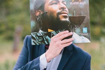 Un homme tient une pochette de disque vinyle devant son visage, alignant le portrait avec sa tête.