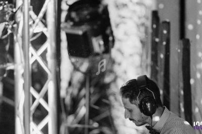 Un DJ portant un casque audio mixe de la musique dans un environnement éclairé par des projecteurs.