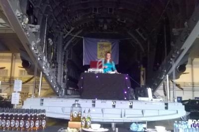 Une DJ joue de la musique sur une scène installée à l'intérieur d'un avion cargo, avec des bouteilles disposées au premier…