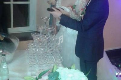 Un couple près d'une pyramide de coupes de champagne, avec des fleurs et une bouteille sur la table.