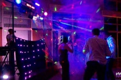 Personnes dansant sous des lumières colorées lors d'une soirée animée par un DJ avec un éclairage vibrant.