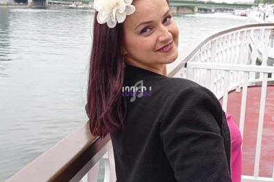 Femme souriante avec une fleur blanche dans les cheveux, posant sur un ponton près de la Seine avec la Tour Eiffel en…