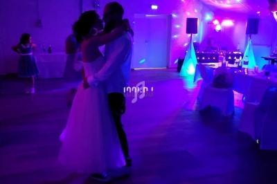 Un couple danse dans une salle éclairée par des lumières colorées lors d'une soirée festive.