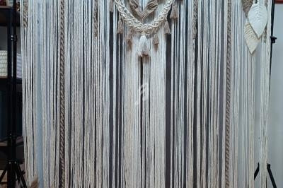 Décor en macramé beige et blanc suspendu, avec des lettres lumineuses formant ’LOVE’ posées au sol.