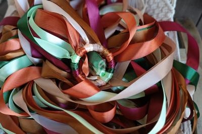 Rubans colorés en satin entremêlés posés sur un support en macramé.