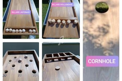 Jeu en bois avec différents plateaux : billard japonais, billard hollandais et cornhole, disposés en extérieur.