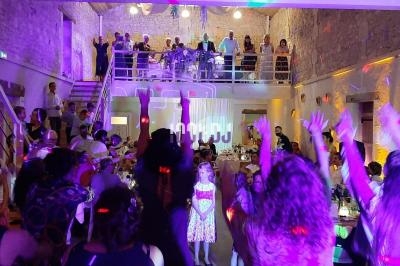 Groupe de personnes dans une salle de réception illuminée, certaines dansant sous des lumières colorées.