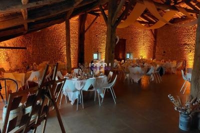 Salle de réception rustique avec murs en pierre, tables décorées et éclairage chaleureux.