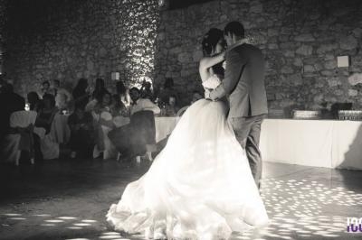 Un couple danse lors de leur mariage dans une salle en pierre éclairée par des lumières tamisées.