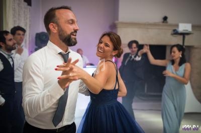 Un couple danse lors d'une réception, entouré d'autres invités en tenue élégante.