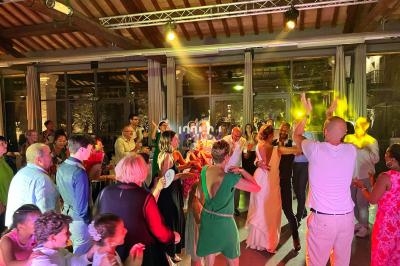 Groupe de personnes dansant et célébrant dans une salle éclairée par des lumières colorées.