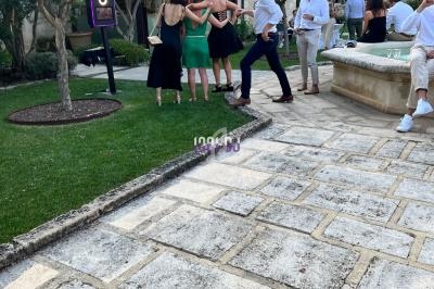 Groupe de personnes posant pour une photo dans un jardin avec des arbres, une fontaine et des pavés au sol.