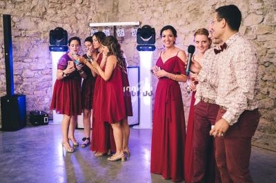Un groupe de personnes en tenue élégante discute et rit dans une salle en pierre avec des lumières colorées.