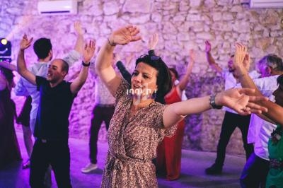 Personnes dansant joyeusement dans une salle en pierre éclairée par des lumières colorées.
