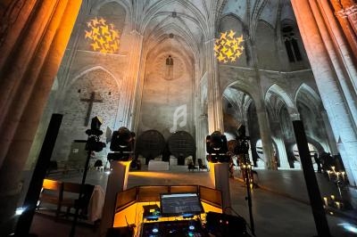 Vue intérieure d'une église gothique éclairée par des projecteurs, avec une table de mixage au premier plan.