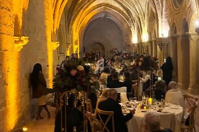 Salle voûtée éclairée avec des invités dînant à des tables décorées de fleurs et de bougies.