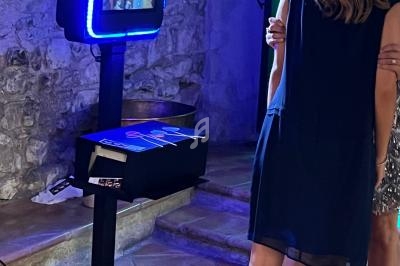 Deux personnes utilisent une borne photo interactive éclairée par un anneau lumineux dans un espace intérieur en pierre.