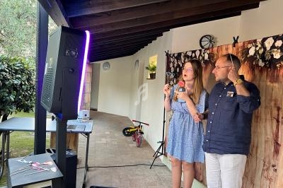 Une femme et un homme utilisent un photobooth sous une pergola, avec un décor floral en arrière-plan.