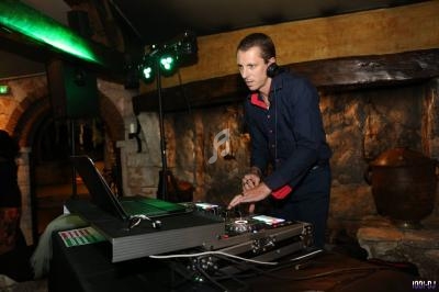 Un DJ mixe de la musique sur une console dans un espace intérieur à l'ambiance rustique.