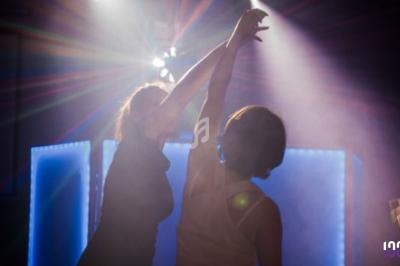 Deux personnes dansent sous des lumières colorées dans une ambiance tamisée.