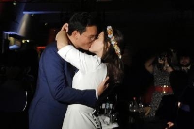 Un couple s'embrasse tendrement dans une ambiance tamisée lors d'un événement festif.