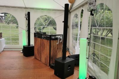 Équipement de sonorisation avec enceintes et éclairages verts installé sous une tente blanche.