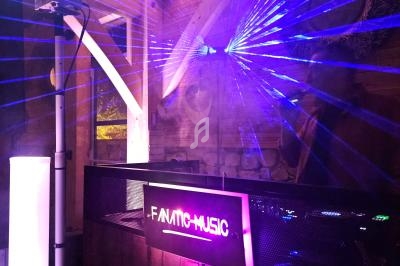 Jeux de lumières violets et bleus projetés dans une ambiance de soirée avec un panneau lumineux ’Fanatic Music’.