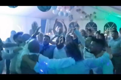 Groupe de personnes dansant et célébrant sous une lumière tamisée dans une salle décorée de ballons.