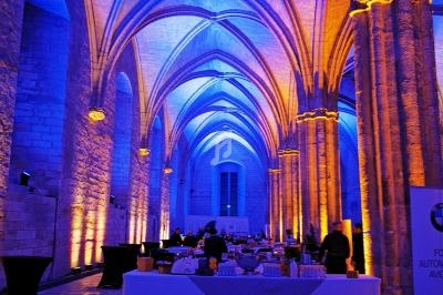Salle voûtée illuminée en bleu et orange, avec des tables dressées pour un événement ou une réception.