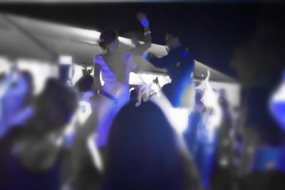 Des personnes dansent et célèbrent sous des lumières bleues dans une ambiance festive en soirée.