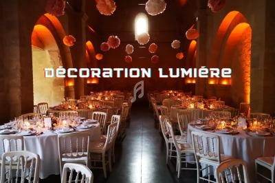 Salle de réception avec tables dressées, éclairage chaleureux et décorations suspendues en papier.