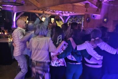 Groupe de personnes dansant en cercle dans une salle en bois éclairée par une lumière tamisée.