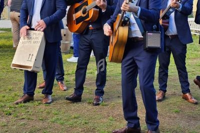 Des musiciens en costume jouent de la guitare en extérieur lors d'un événement, entourés de participants.