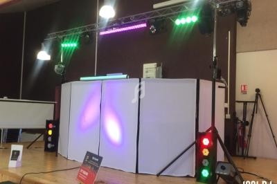 Installation de matériel de sonorisation et d'éclairage sur une scène avec projecteurs colorés et table de mixage.