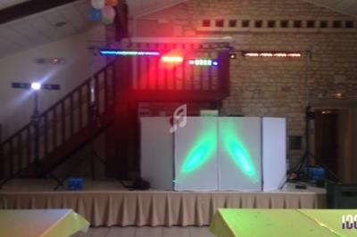 Installation de matériel de sonorisation et éclairage coloré dans une salle avec murs en pierre et plafond en bois.