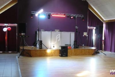 Scène de salle de réception avec éclairage coloré, enceintes et matériel de sonorisation installé.