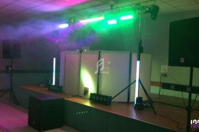 Équipement de sonorisation et éclairage coloré installé sur une scène dans une salle intérieure.