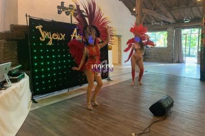 Deux danseuses en costumes colorés et plumes se produisent sur une scène dans une salle festive.