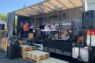 Un groupe de musiciens joue sur une scène extérieure équipée d'instruments et de matériel de sonorisation.