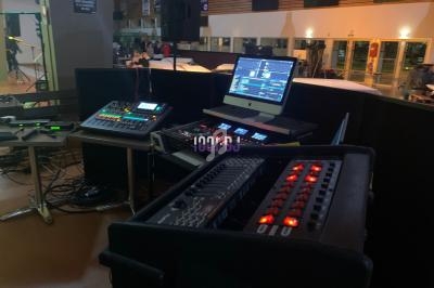 Poste de régie technique avec consoles audio, ordinateur et équipements de mixage dans une salle événementielle.
