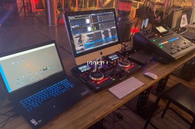 Poste de travail de DJ avec ordinateurs, platines, table de mixage et éclairage d'ambiance dans un studio.