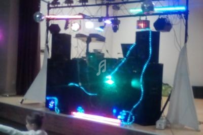 Installation de matériel de sonorisation et d'éclairage coloré sur une scène intérieure lors d'un événement.