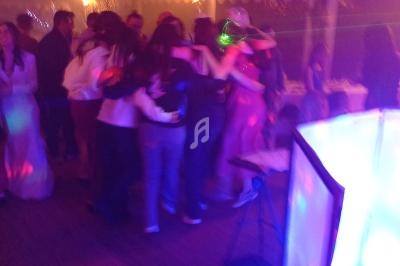 Groupe de personnes dansant sous une tente éclairée par des lumières colorées lors d'un événement festif.