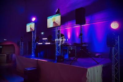 Installation de matériel de sonorisation et d'éclairage avec écrans et projecteurs dans une salle sombre.