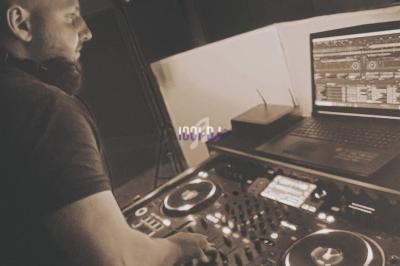 Un DJ mixant de la musique sur une table de mixage avec un ordinateur portable à ses côtés dans un studio.